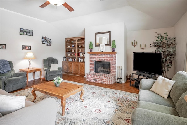 living room featuring a brick fireplace, vaulted ceiling, light hardwood / wood-style floors, and ceiling fan