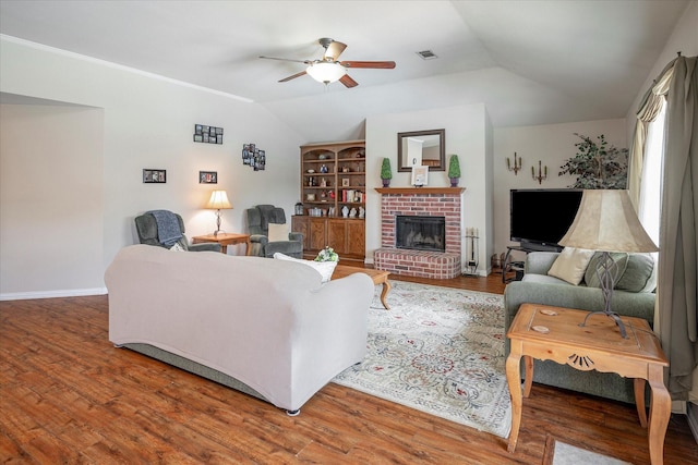 living room with a brick fireplace, wood-type flooring, ceiling fan, and vaulted ceiling