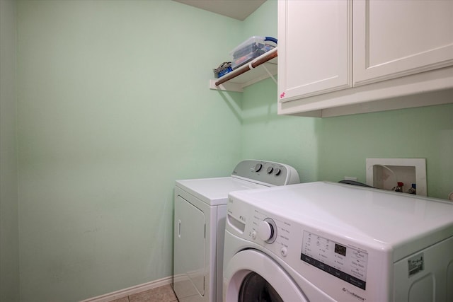 washroom featuring cabinets, washing machine and dryer, and light tile patterned floors