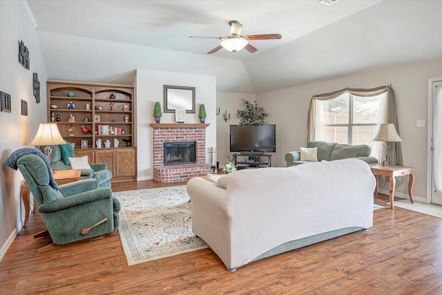 living room featuring hardwood / wood-style flooring, lofted ceiling, ceiling fan, and a brick fireplace