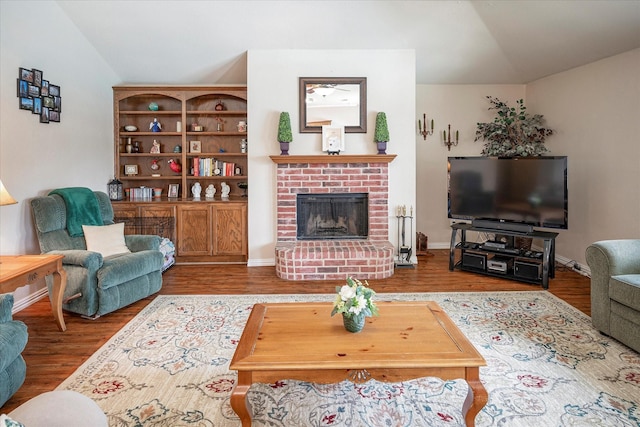 living room featuring hardwood / wood-style flooring, vaulted ceiling, and a fireplace