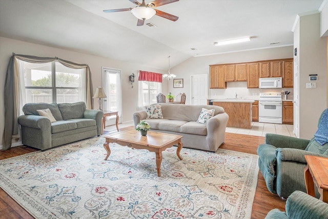 living room featuring ceiling fan with notable chandelier, lofted ceiling, sink, crown molding, and light hardwood / wood-style flooring