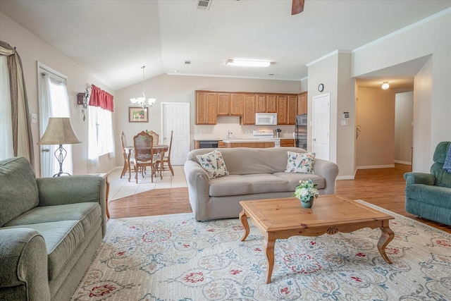 living room featuring crown molding, lofted ceiling, a chandelier, and light hardwood / wood-style floors