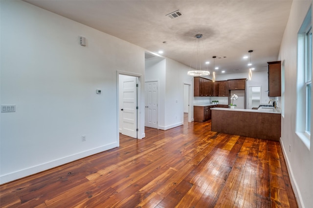 kitchen with sink, stainless steel fridge, dark hardwood / wood-style flooring, a kitchen island, and pendant lighting