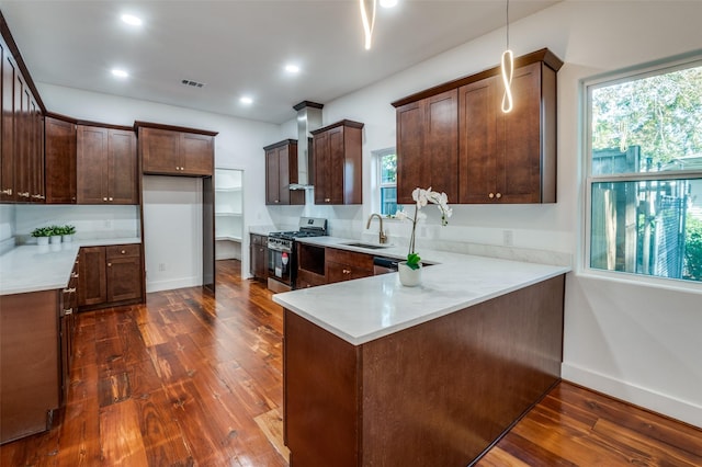 kitchen with gas range, dark hardwood / wood-style floors, kitchen peninsula, and sink