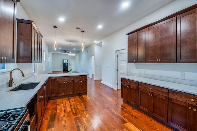 kitchen featuring light stone counters, decorative light fixtures, kitchen peninsula, and sink