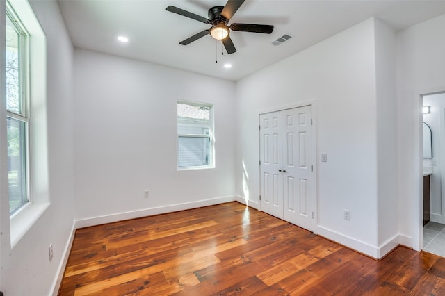 unfurnished bedroom with a closet, dark hardwood / wood-style floors, ceiling fan, and ensuite bathroom