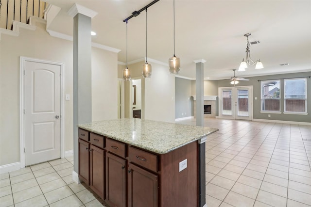 kitchen with pendant lighting, crown molding, ceiling fan, light stone countertops, and light tile patterned flooring