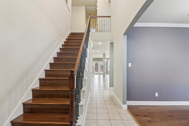 staircase featuring crown molding, tile patterned floors, and a high ceiling