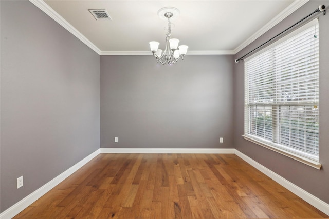 spare room featuring an inviting chandelier, crown molding, and hardwood / wood-style flooring