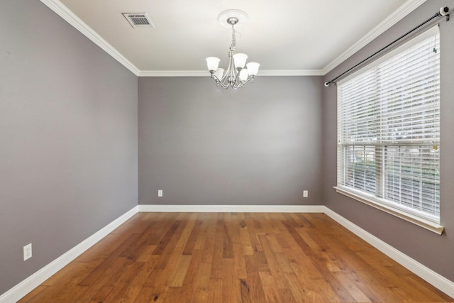 empty room featuring hardwood / wood-style flooring, crown molding, and a chandelier