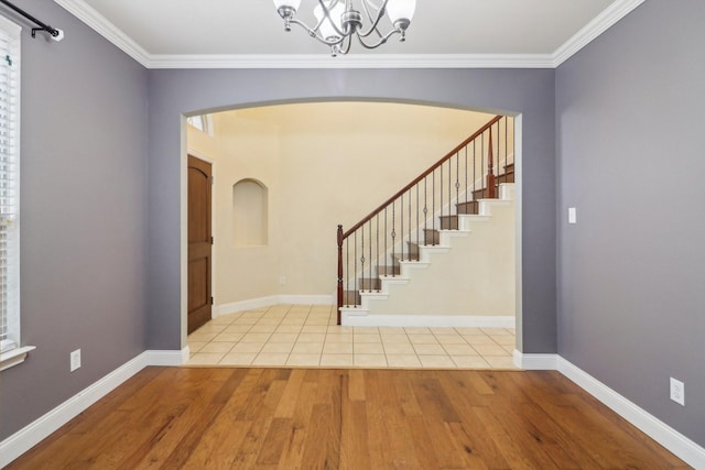 foyer entrance with crown molding, light wood-type flooring, and an inviting chandelier