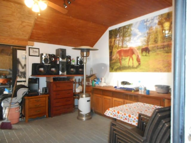 interior space with wood ceiling, tile counters, ceiling fan, and vaulted ceiling