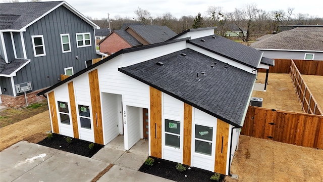 rear view of property featuring a shingled roof, a fenced backyard, and a patio