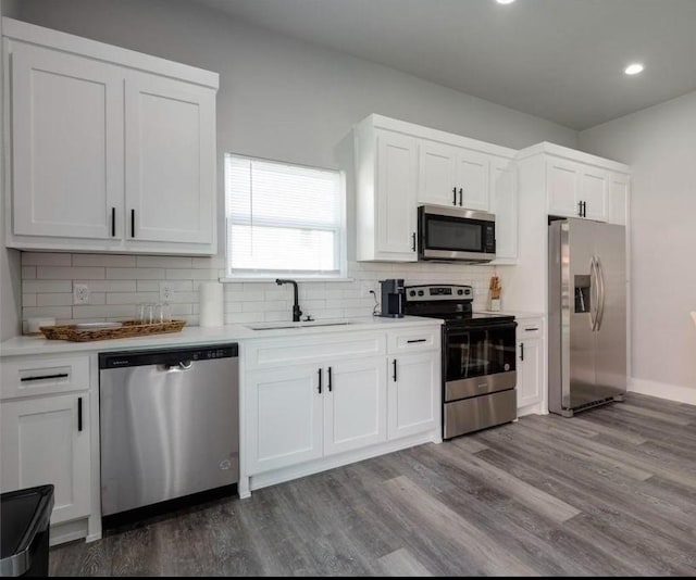 kitchen with appliances with stainless steel finishes, dark wood-style flooring, white cabinetry, and a sink