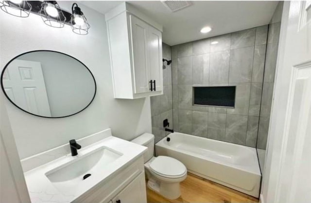 bathroom featuring shower / bathtub combination, visible vents, toilet, vanity, and wood finished floors