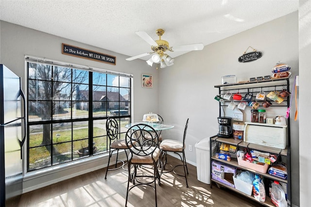 dining space with ceiling fan, a textured ceiling, wood-type flooring, and a healthy amount of sunlight