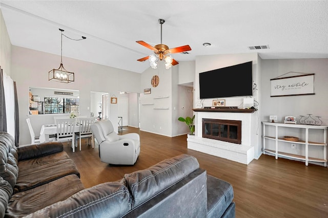 living room featuring high vaulted ceiling, dark hardwood / wood-style floors, ceiling fan with notable chandelier, and a brick fireplace