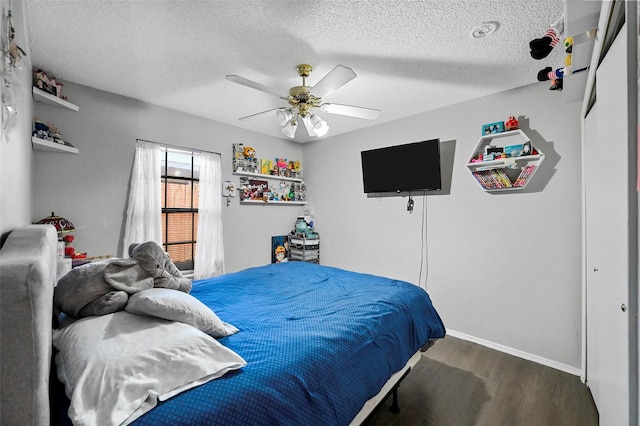 bedroom with ceiling fan, dark wood-type flooring, and a textured ceiling