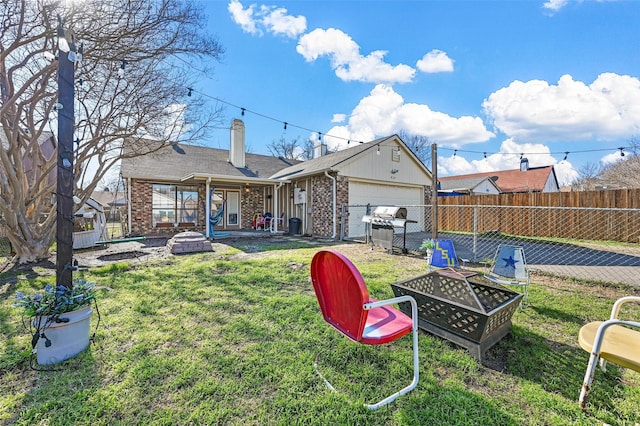 back of house with a yard and an outdoor fire pit