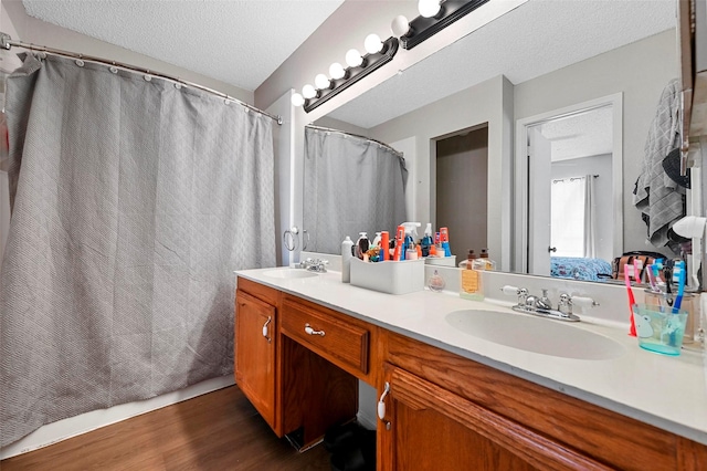 bathroom featuring vanity, curtained shower, wood-type flooring, and a textured ceiling