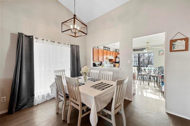 dining area featuring wood-type flooring, ceiling fan with notable chandelier, and high vaulted ceiling