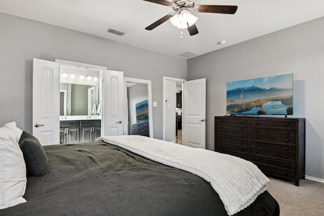 bedroom with ceiling fan, ensuite bathroom, and light carpet