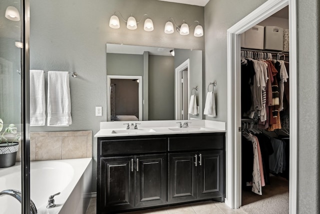 bathroom with a washtub, vanity, and tile patterned flooring