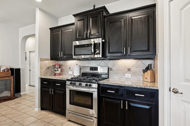 kitchen featuring light stone counters, light tile patterned floors, decorative backsplash, and appliances with stainless steel finishes