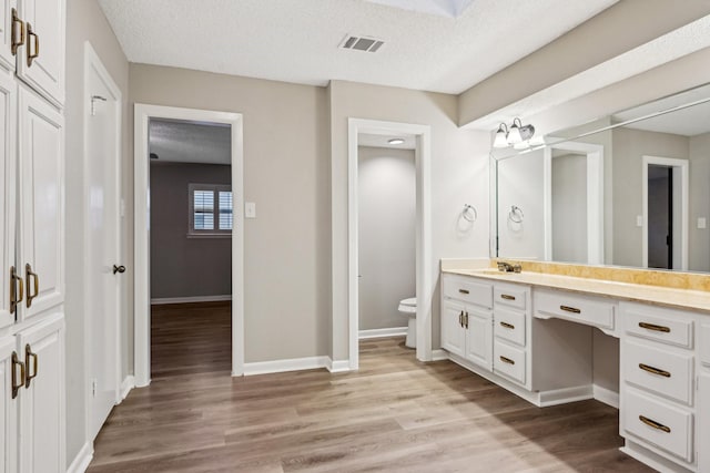 201 Trailwood Dr, Euless, TX 76039 - bathroom with vanity, wood-type flooring, toilet, and a textured ceiling