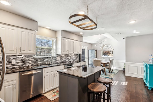 kitchen featuring stainless steel appliances, a kitchen island, sink, and white cabinets