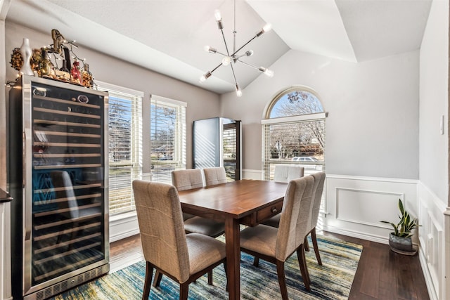 dining space featuring wine cooler, lofted ceiling, wood-type flooring, and a chandelier