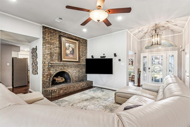 living room with hardwood / wood-style flooring, ornamental molding, a fireplace, and ceiling fan with notable chandelier