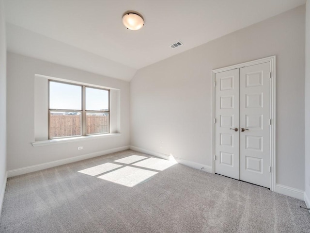 carpeted empty room with lofted ceiling