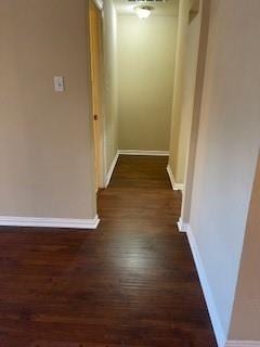 corridor with baseboards and dark wood finished floors