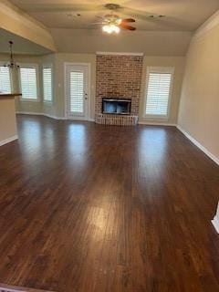 unfurnished living room with a brick fireplace, dark wood-type flooring, lofted ceiling, and ceiling fan