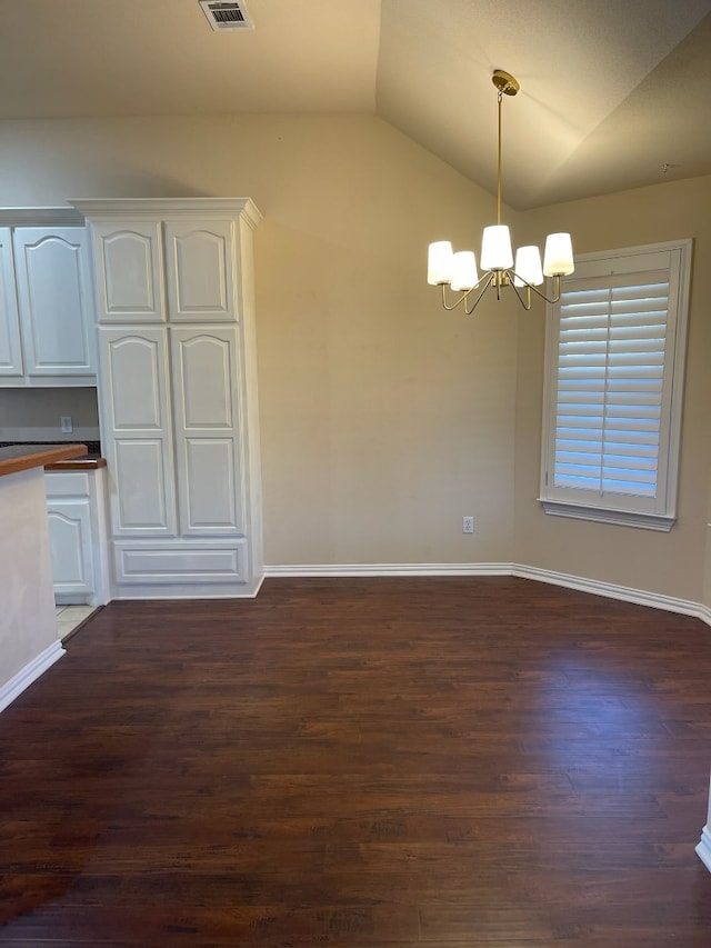 unfurnished dining area featuring baseboards, a chandelier, vaulted ceiling, and dark wood finished floors