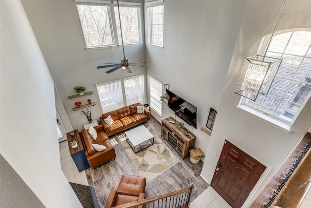 tiled living room with ceiling fan and a high ceiling