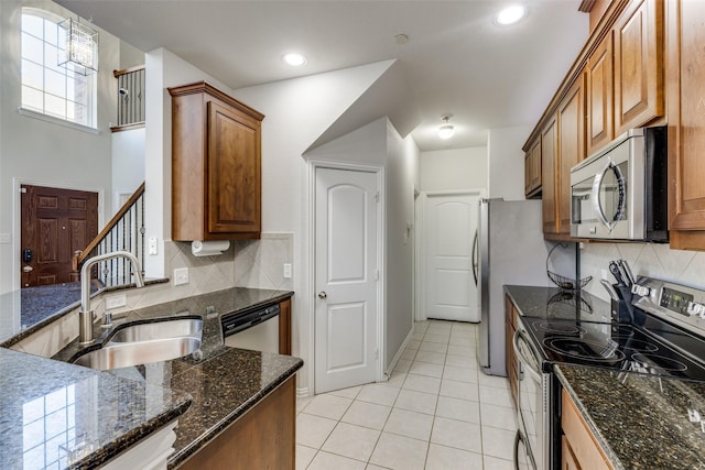 kitchen featuring light tile patterned floors, stainless steel appliances, sink, and dark stone countertops