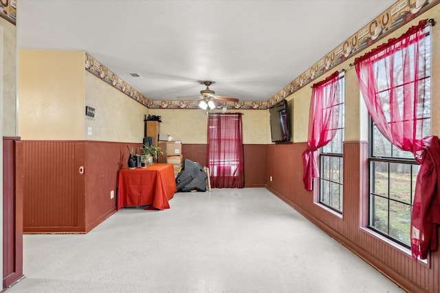 interior space with ceiling fan and wood walls