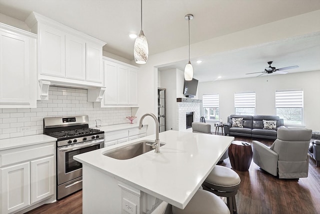 kitchen with white cabinetry, stainless steel gas range, and a kitchen island with sink