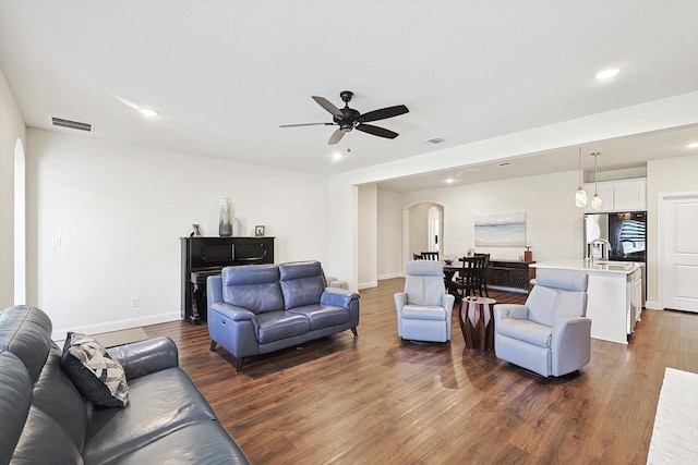 living room featuring ceiling fan, sink, and dark hardwood / wood-style flooring