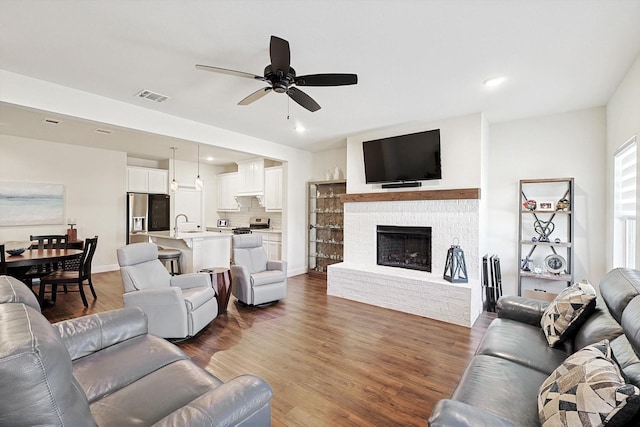 living room with a fireplace, dark hardwood / wood-style floors, and ceiling fan