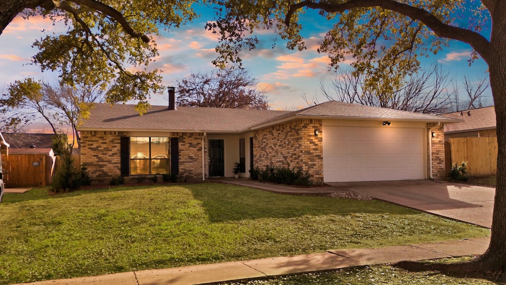 ranch-style house with brick siding, a yard, a chimney, concrete driveway, and an attached garage