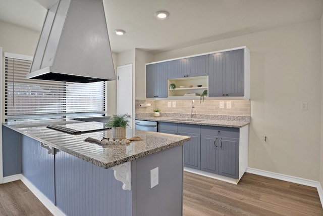 kitchen with ventilation hood, light stone countertops, a breakfast bar area, and kitchen peninsula