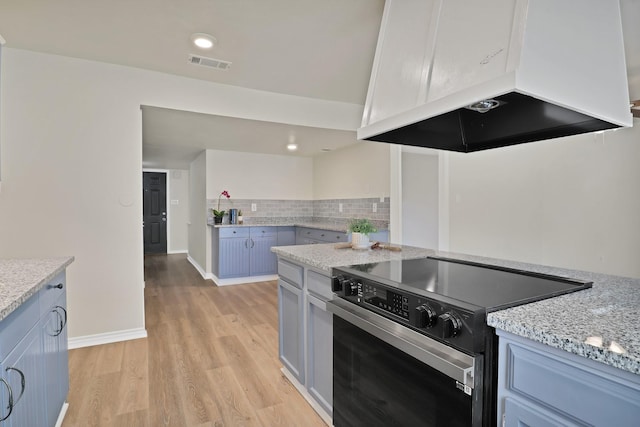 kitchen featuring extractor fan, electric range oven, decorative backsplash, light stone counters, and light hardwood / wood-style floors