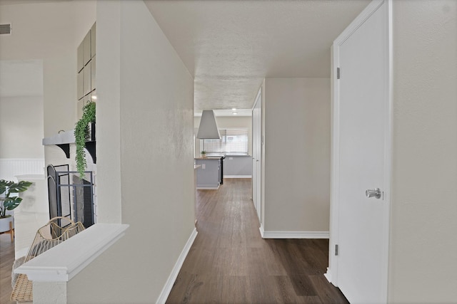 hallway with a textured ceiling and dark hardwood / wood-style flooring