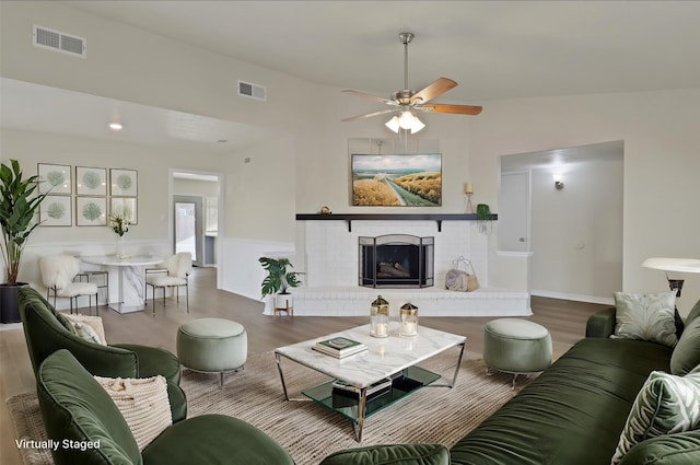 living room featuring hardwood / wood-style flooring, ceiling fan, lofted ceiling, and a brick fireplace