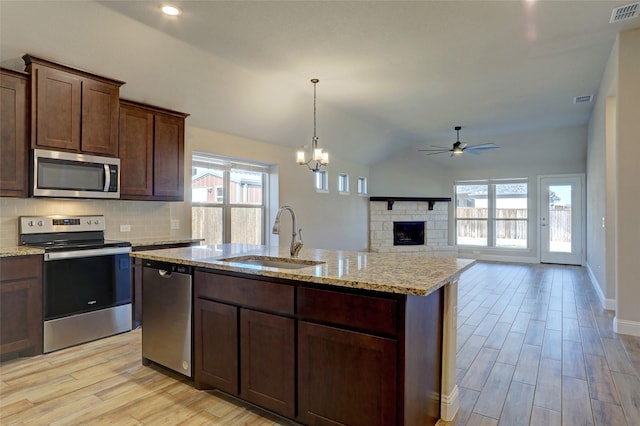 kitchen with a fireplace, a sink, visible vents, appliances with stainless steel finishes, and light wood-type flooring