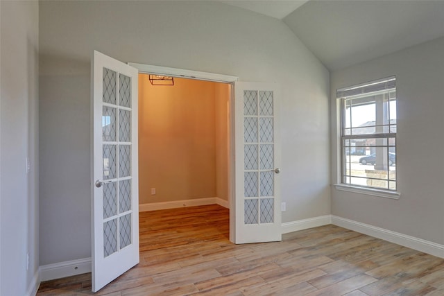 unfurnished room featuring lofted ceiling, french doors, and wood finished floors